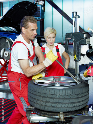 Photo: Car mechanic with tyre lever is fitting a summer tyre Car mechanic with tyre lever is fitting a summer tyre