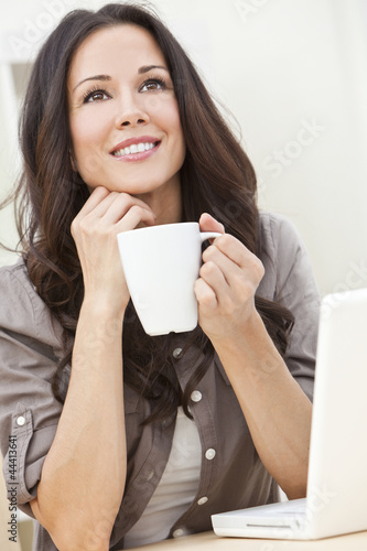 Photo: Beautiful Woman Using a Computer and Drinking Tea or Coffee Beautiful Woman Using a Computer and Drinking Tea or Coffee