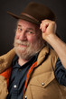 Friendly elderly man smiles and tips his hat