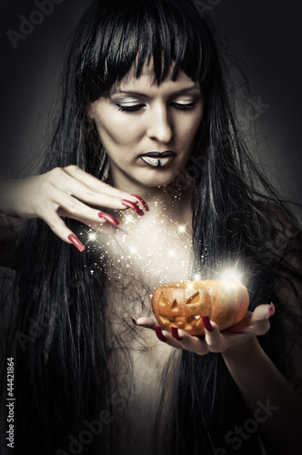 Photo: woman witch making magic to pumpkin woman witch making magic to pumpkin