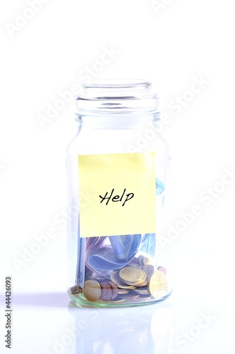 Photo: Glass jar with coins and word help. Glass jar with coins and word help.