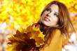Young woman with autumn leaves in hand and fall yellow maple gar