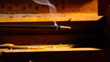 Incense stick in a wooden holder with red silk background, artit