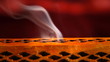 Incense stick in a wooden holder with red silk background, artit
