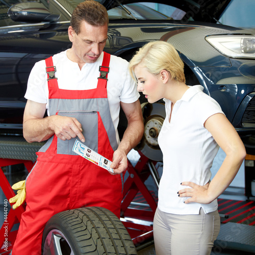 Photo: Motor mechanic explains to a customer tire labeling in a garage Motor mechanic explains to a customer tire labeling in a garage
