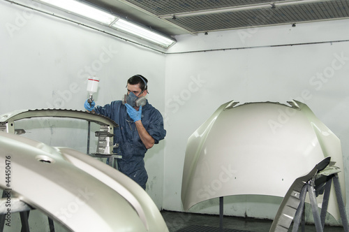 Photo: Man painting car parts. Man painting car parts.