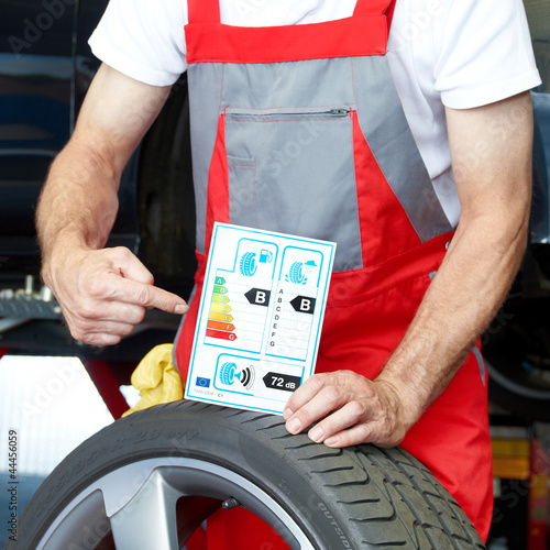 Photo: Car mechanic showcases tire label Car mechanic showcases tire label