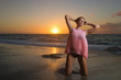 Ragazza in posa sulla riva del mare al tramonto