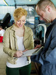 Customer and mechanic in a garage looking at a quotation