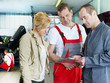 Customer and two mechanics discussing the repair costs of a car