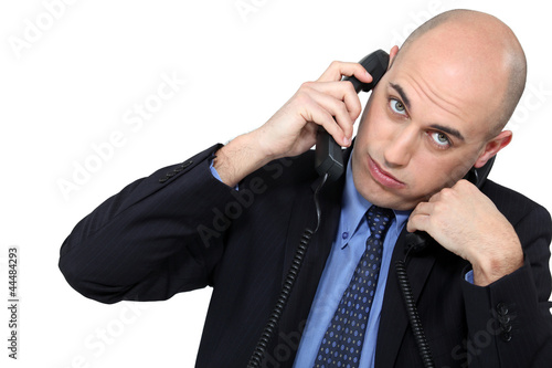 Photo: Businessman using two phones Businessman using two phones