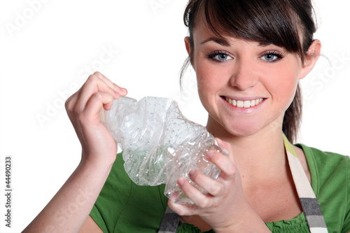 Photo: young girl squashing plastic bottle young girl squashing plastic bottle