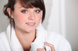Brunette in bathrobe drinking coffee