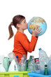 Little girl kissing planet earth next to her recycling