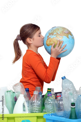Photo: Little girl kissing planet earth next to her recycling Little girl kissing planet earth next to her recycling