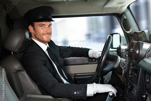 Photo: Handsome chauffeur driving limousine smiling Handsome chauffeur driving limousine smiling