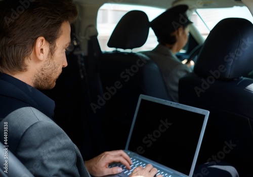Photo: Young man in limousine using laptop computer Young man in limousine using laptop computer