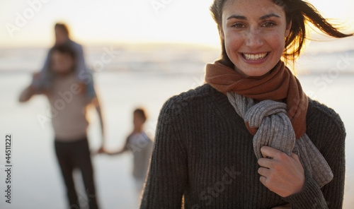 Photo: Portrait of smiling woman on beach with family in background Portrait of smiling woman on beach with family in background