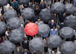 Red umbrella standing out in crowd of business people