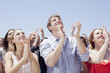 Crowd of smiling people clapping and looking up