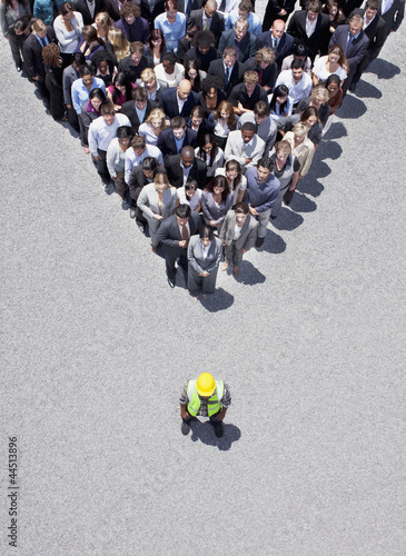 Photo: Construction worker at apex of pyramid formed by business people Construction worker at apex of pyramid formed by business people