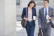 Smiling businessman and businesswoman walking with coffee cups