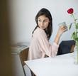 Woman at table drinking coffee and looking back