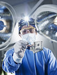 Portrait of surgeon holding one hundred dollar bill under surgical lights