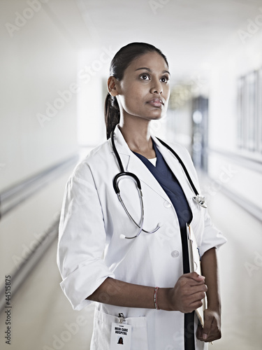Photo: Portrait of pensive doctor holding medical record in hospital corridor Portrait of pensive doctor holding medical record in hospital corridor