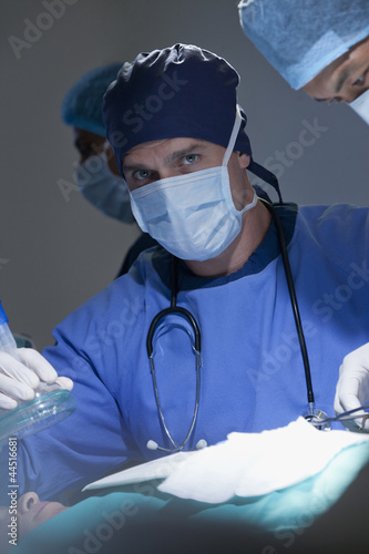 Photo: Portrait of serious surgeon holding oxygen mask over patient in operating room Portrait of serious surgeon holding oxygen mask over patient in operating room