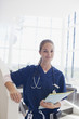Portrait of confident nurse holding medical record in hospital