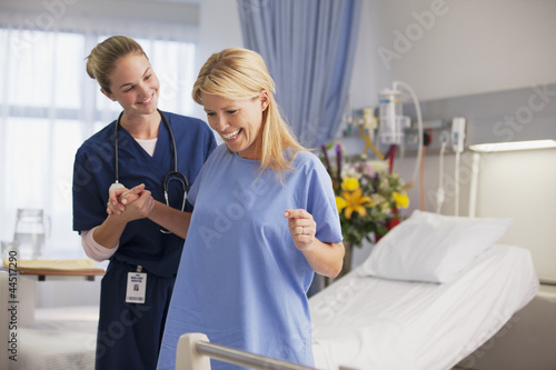 Photo: Nurse helping happy patient stand in hospital room Nurse helping happy patient stand in hospital room