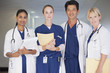Portrait of smiling doctors and nurse holding medical records in hospital corridor
