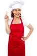 Beautiful smiling female chef indicating upwards