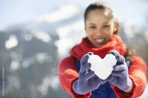 Photo: Portrait of smiling woman holding heart-shape snowball Portrait of smiling woman holding heart-shape snowball