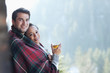 Portrait of smiling couple wrapped in a blanket and drinking hot cider on porch