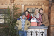 Photo: Portrait of smiling couples with fresh cut Christmas tree and gifts in front of cabin Portrait of smiling couples with fresh cut Christmas tree and gifts in front of cabin