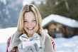 Portrait of smiling woman holding Christmas gift in front of cabin