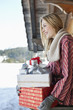 Smiling woman holding Christmas gifts on cabin porch