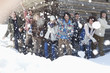Portrait of smiling friends throwing snowballs in front of cabin