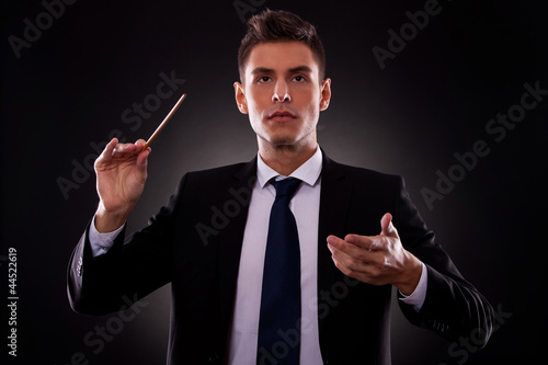 Photo: Young businessman directing with a conductor's stick Young businessman directing with a conductor's stick