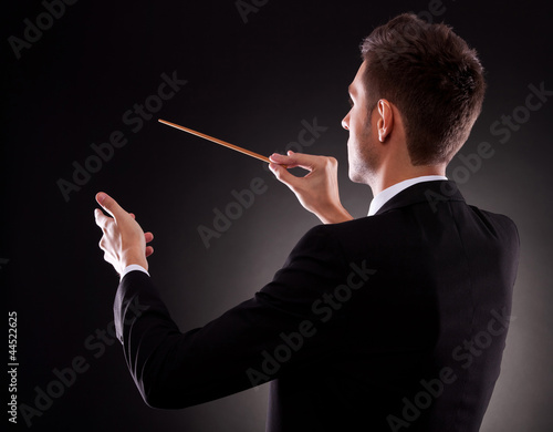Photo: Back view of a young composer directing with his baton Back view of a young composer directing with his baton