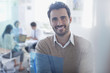 Portrait of smiling businessman in conference room with co-workers in background