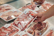 Packaged meat with woman hand in the supermarket