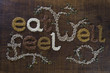 The phrase 'Eat Well, Be Well', written and decorated in seeds