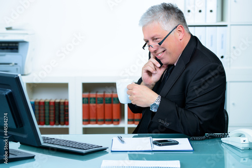 Foto: seniorchef trinkt kaffee beim telefonieren seniorchef trinkt kaffee beim telefonieren