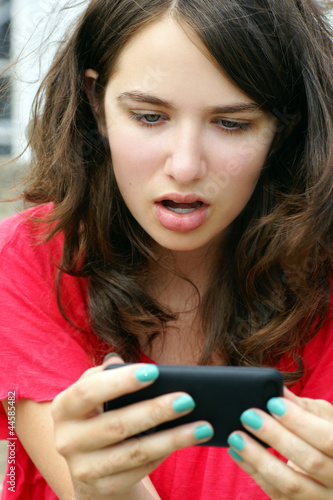 Foto: Girl in disbelief over mobile or cell phone text Girl in disbelief over mobile or cell phone text
