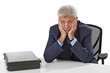 Frustrated senior business man rests chin on hands 