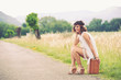 Photo: Beautiful girl waiting on a country road with her suitcase. Beautiful girl waiting on a country road with her suitcase.