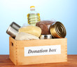 Donation box with food on blue background close-up